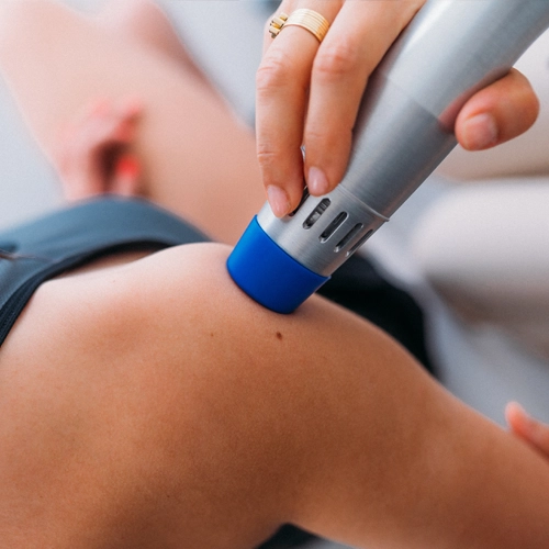 A practitioner using laser therapy on a patient's shoulder