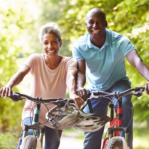 An active, happy couple biking on a trail in a wooded area